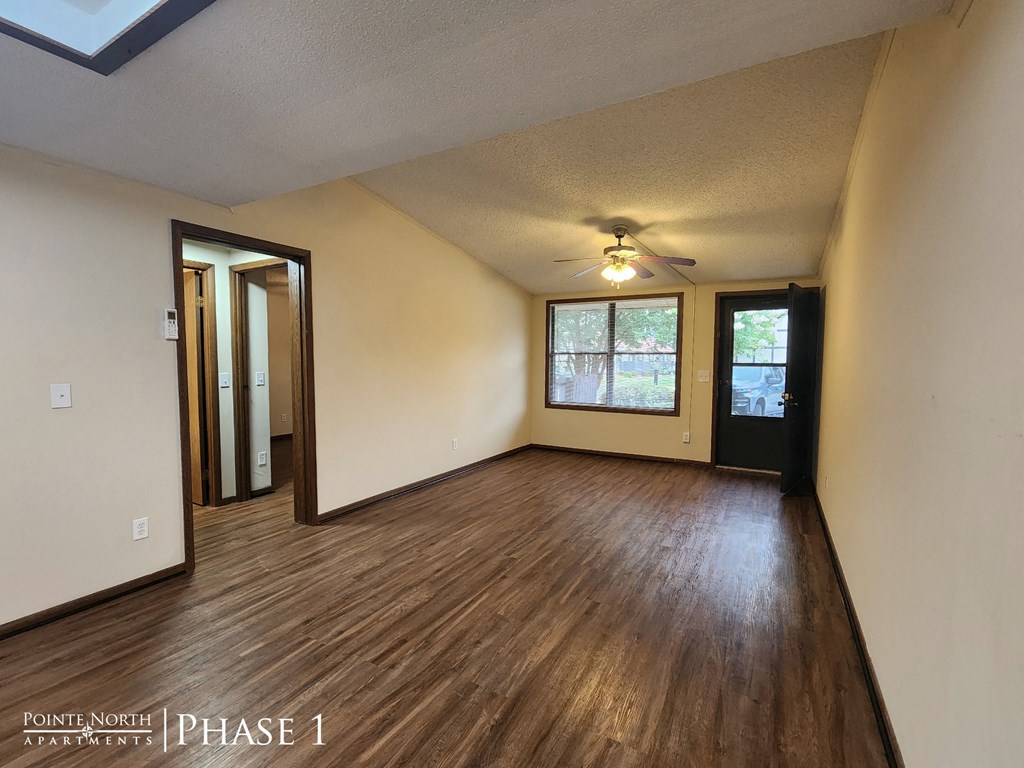 an empty living room with wood floors and a ceiling fan