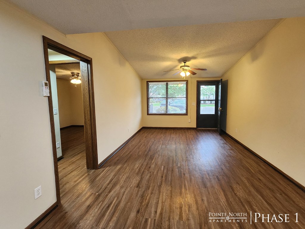 the living room of an empty house with wooden floors and a ceiling fan
