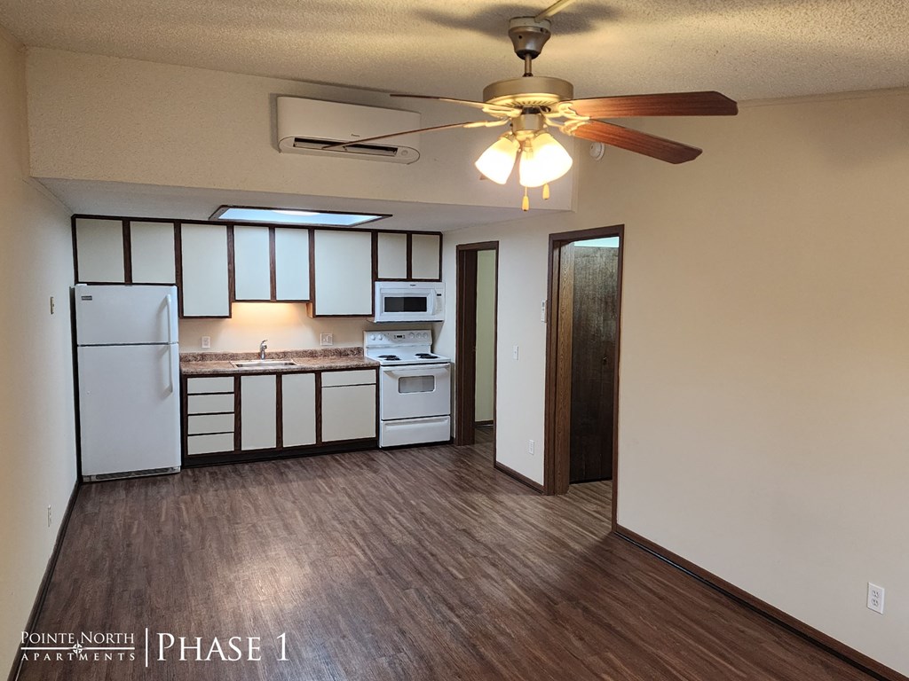 an empty kitchen with a ceiling fan and white appliances