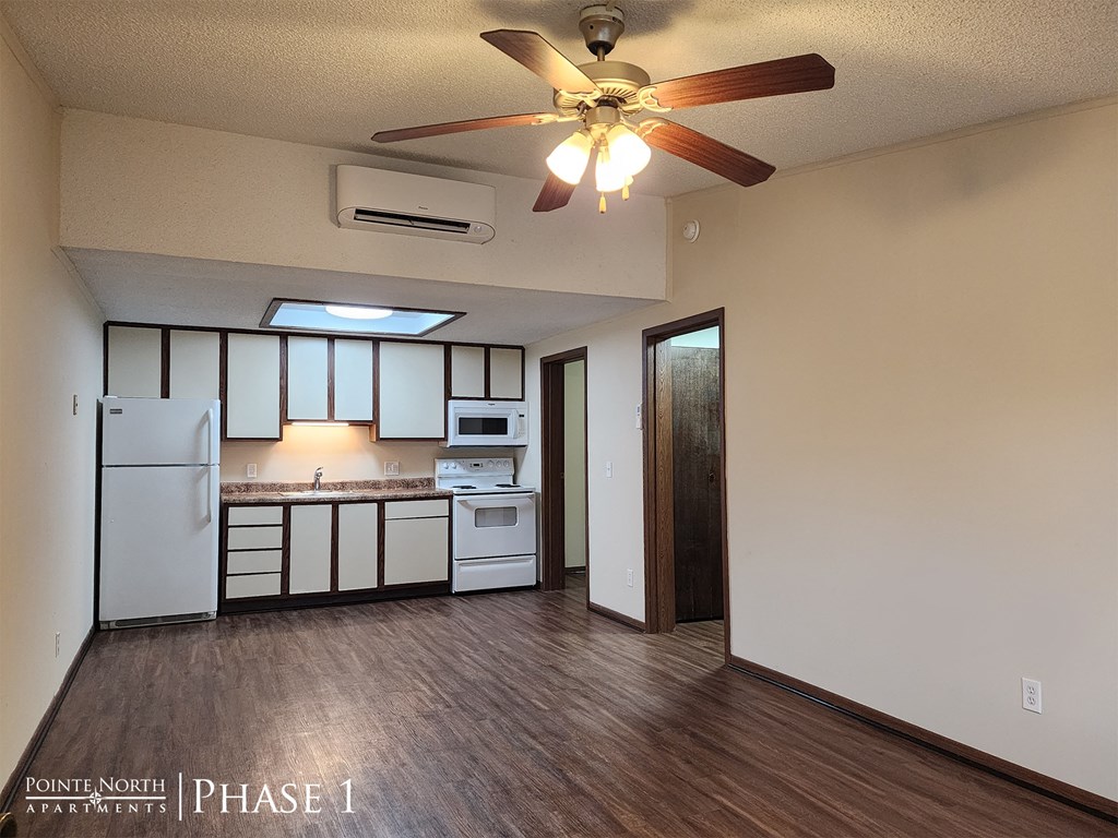 a kitchen with white appliances and a ceiling fan