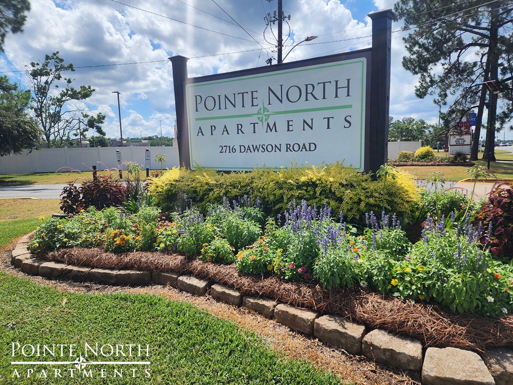 a sign for pointe north apartments in front of a flower garden