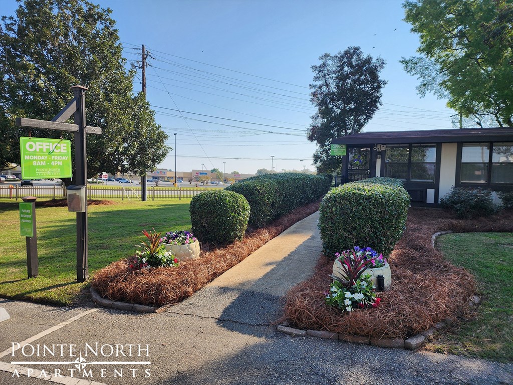 a sidewalk in front of a building with a green sign