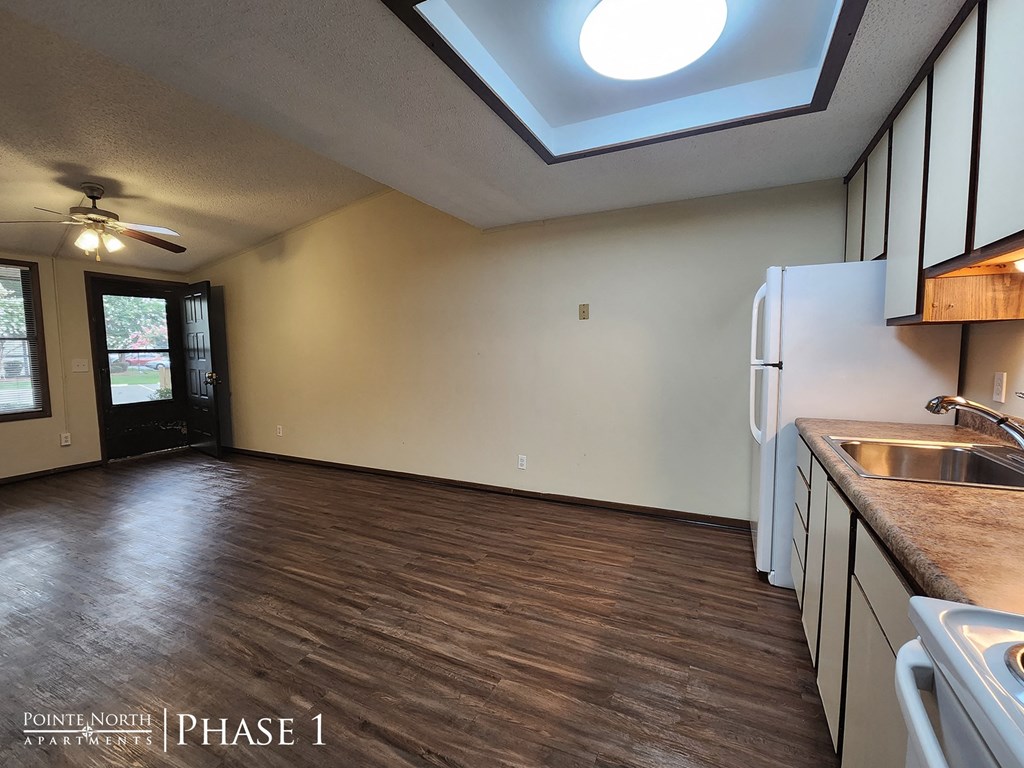 a kitchen and living room with a refrigerator and a sink