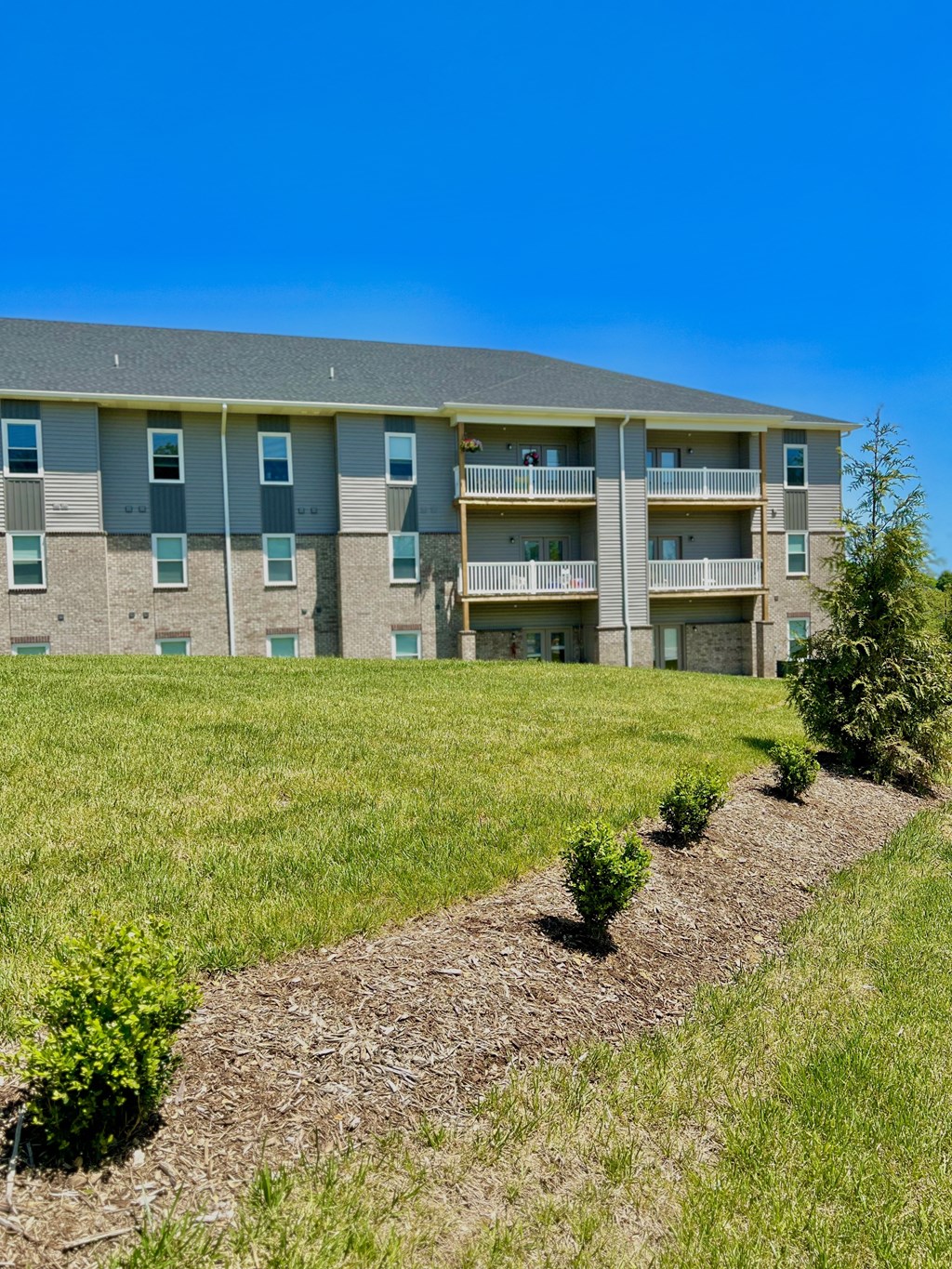 an apartment building with grass and bushes in front of it