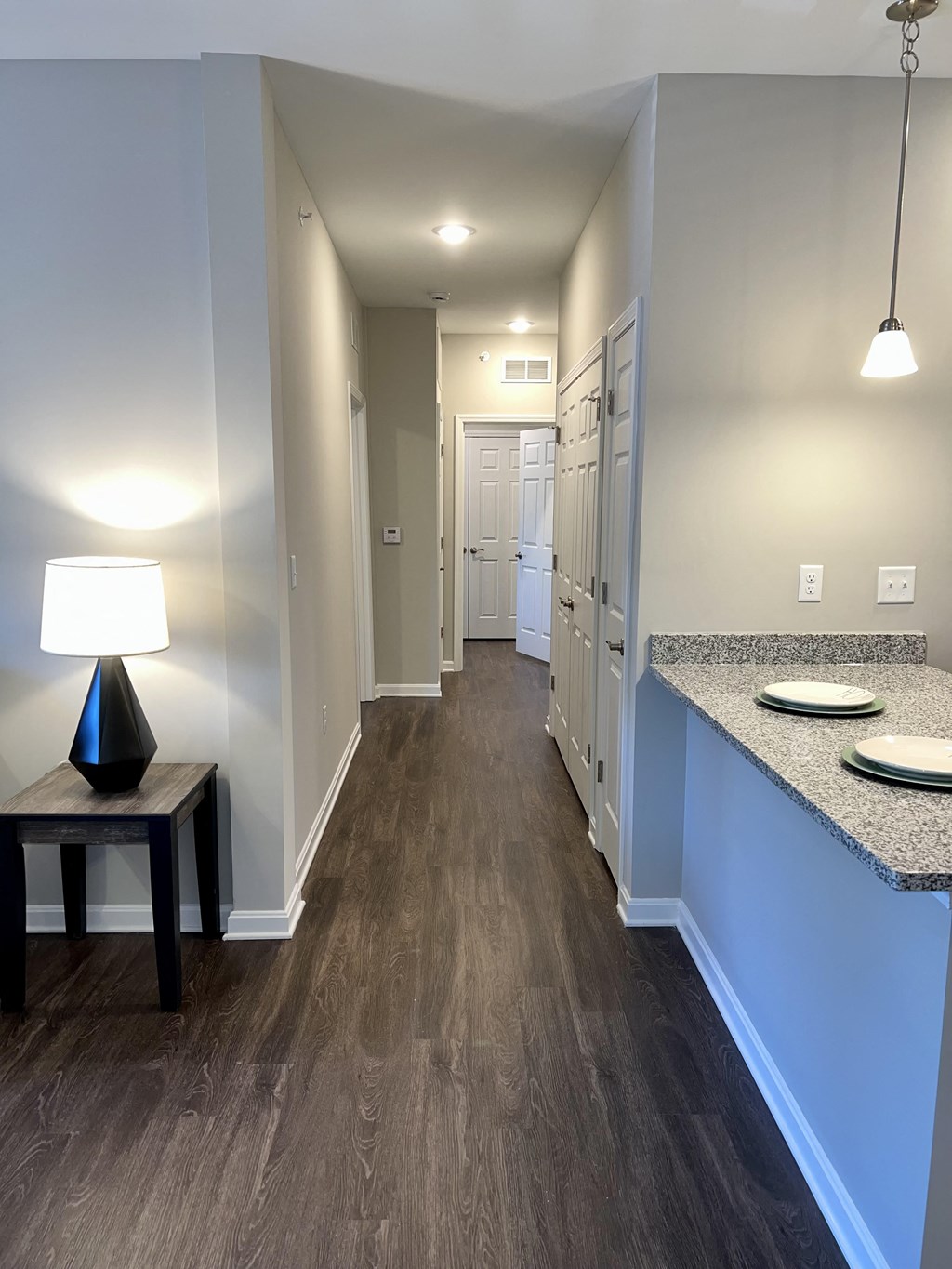 a long hallway with a counter and a table with a lamp