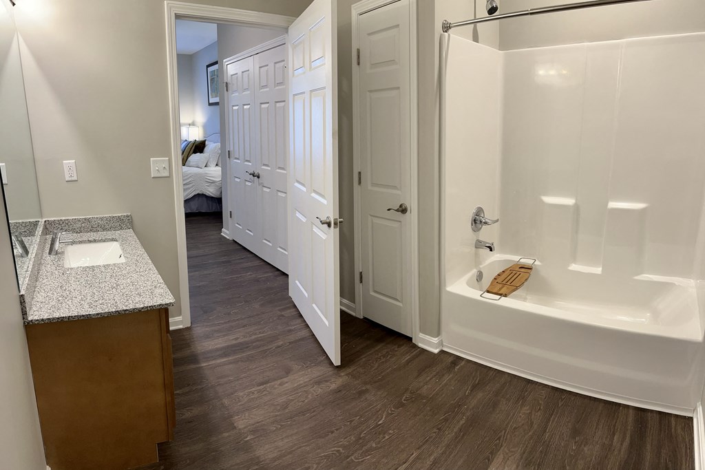 a bathroom with a tub and a sink and a doorway to a bedroom