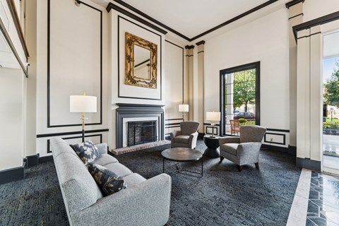 A living room with a grey couch, a fireplace, and a painting on the wall.