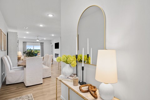 A modern living room with a white sofa set, a wooden coffee table, and a large arched mirror.