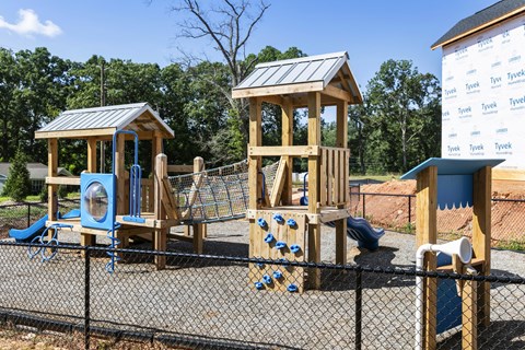 A playground with a wooden swing set and a blue slide.