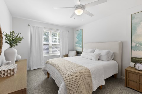 A bedroom with a large bed and a ceiling fan.