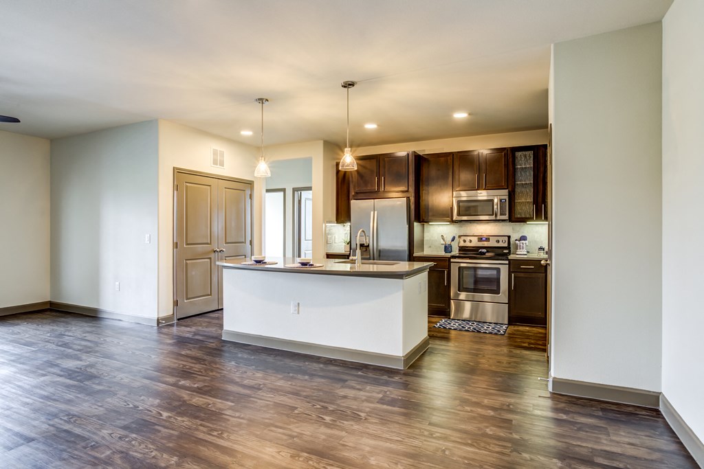 an open kitchen and living room with a white island and wood floors
