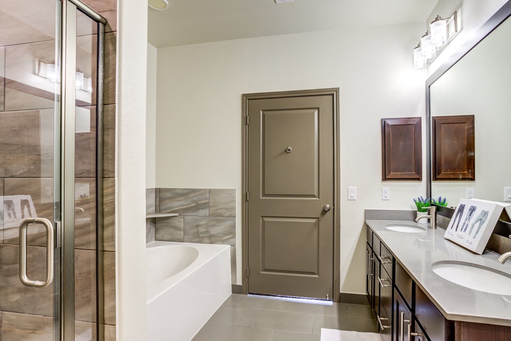 a bathroom with a tub and a shower and a sink and a door