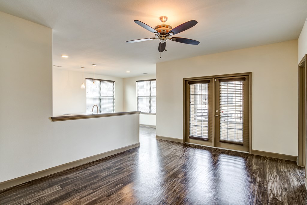 an empty living room with a ceiling fan and a kitchen