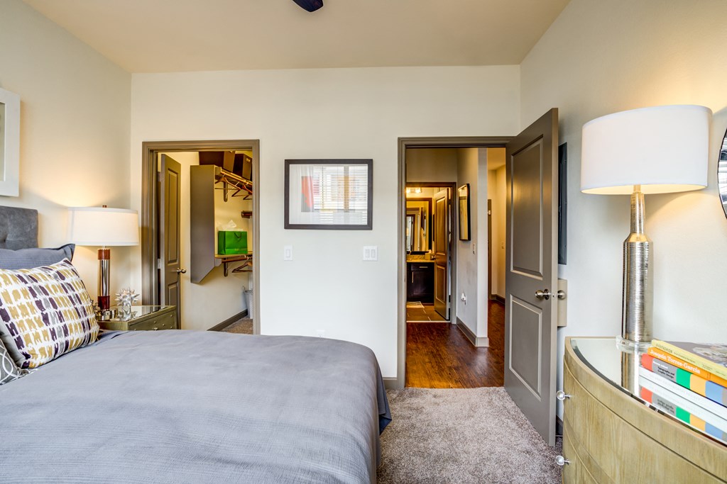 a bedroom with a bed and a dresser and a door to a bathroom