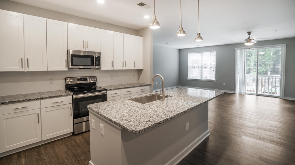 an empty kitchen with granite counter tops and white cabinets