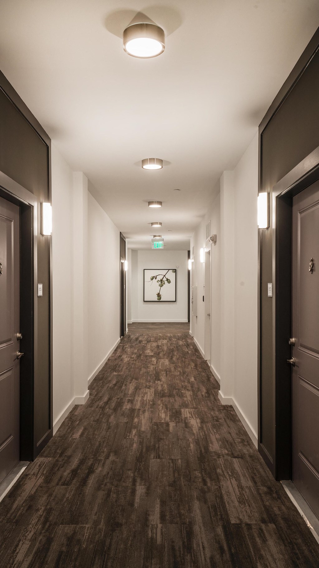 a corridor with doors and a clock on the wall at the end of a hallway