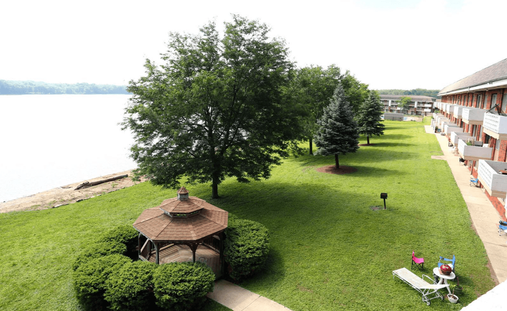 A gazebo sits in the middle of a grassy area next to a body of water.
