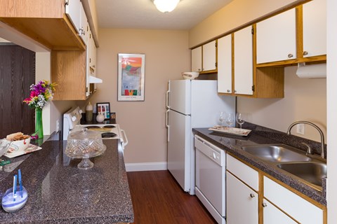 A kitchen with a granite counter top and white appliances.
