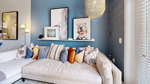 A living room with a white couch and a painting of a dog on the wall.