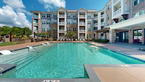 A large swimming pool in front of a multi-story apartment building.