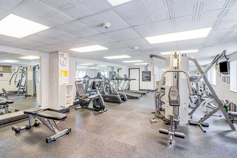 A gym with a variety of equipment including treadmills, weights, and exercise machines.