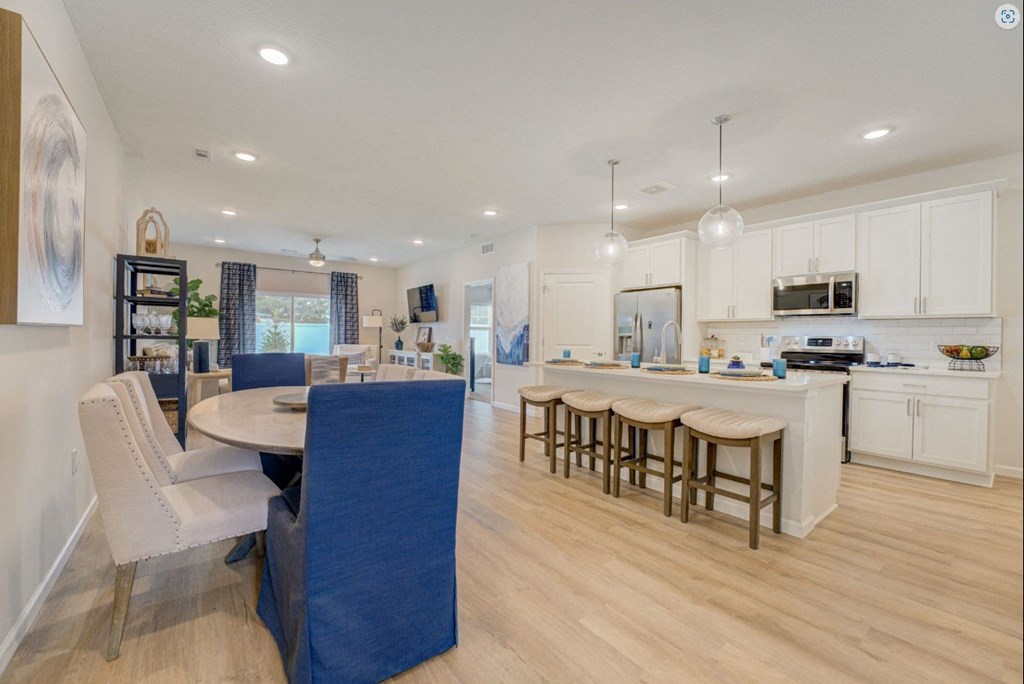 an open kitchen and dining area with white cabinets and a table and chairs