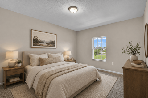 A bedroom with a large bed, a nightstand with a lamp, and a framed picture on the wall.