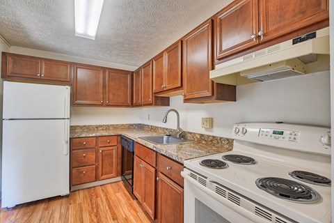 A kitchen with white appliances and wooden cabinets.