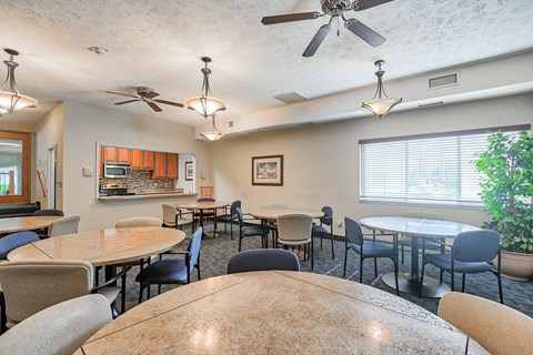 A dining room with a table surrounded by chairs and a ceiling fan.