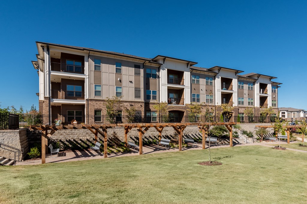 an image of an apartment building with lawns and chairs in front of it