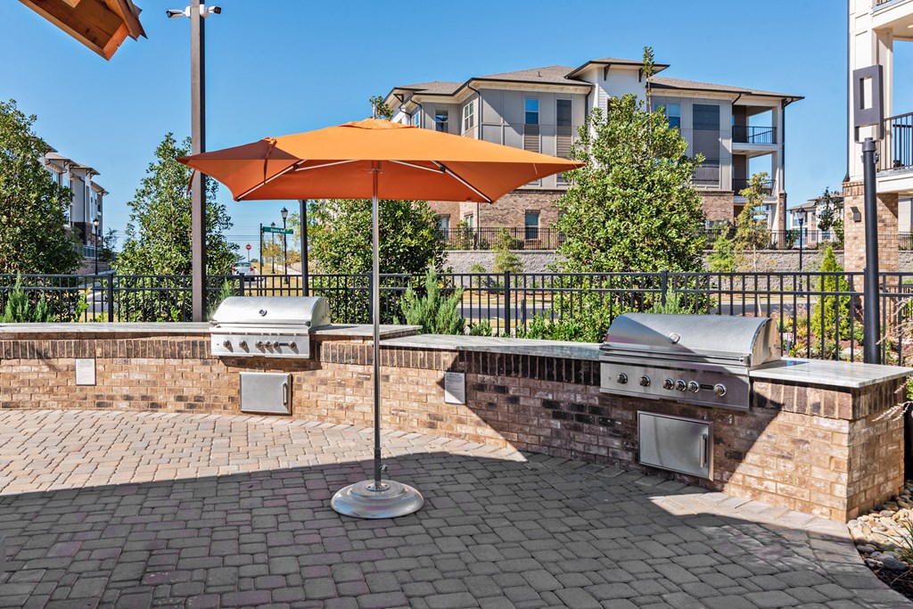 a patio with an umbrella and a barbecue grill