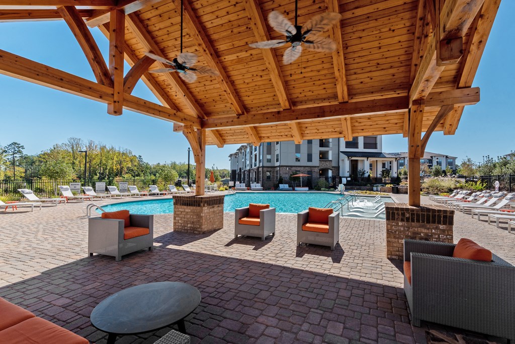 the resort style pool is under a wooden pavilion with chairs