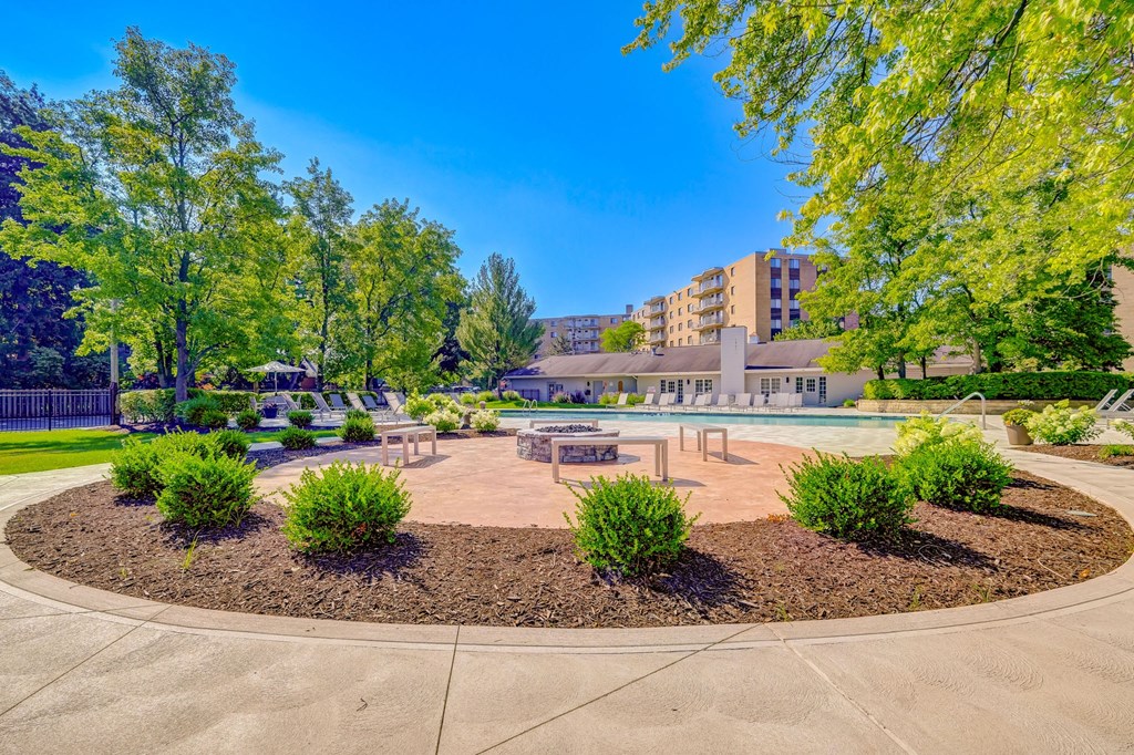 a park with a fountain and trees with a building in the background