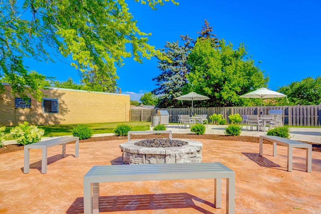 a patio with tables and chairs and a fire pit