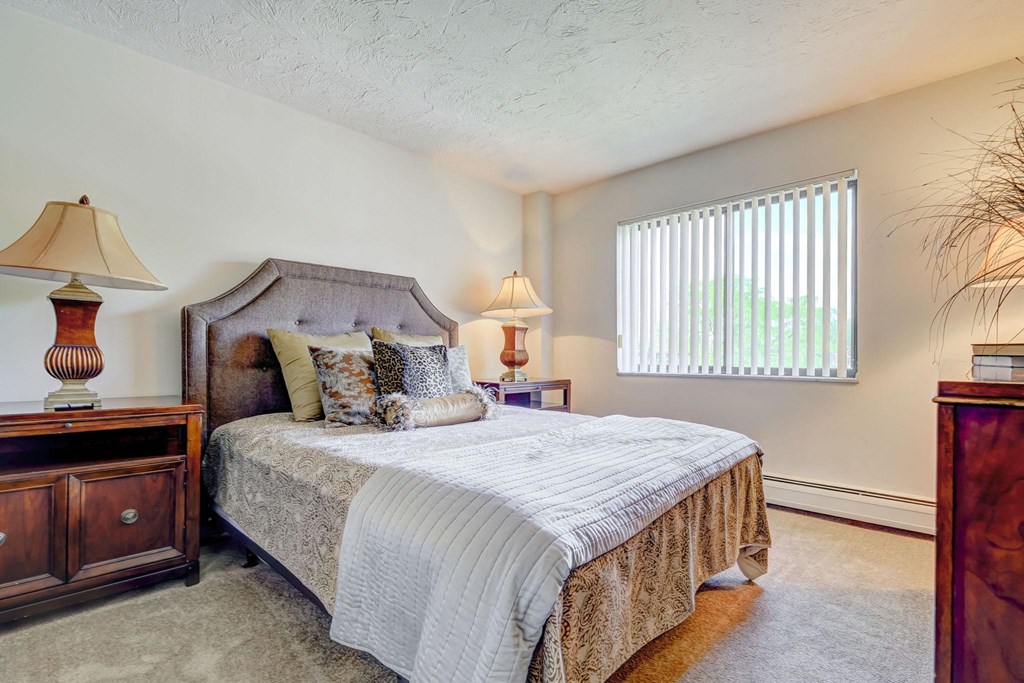 a bedroom with a bed and two lamps and a window