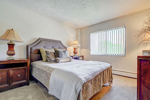 a bedroom with a bed and two lamps and a window