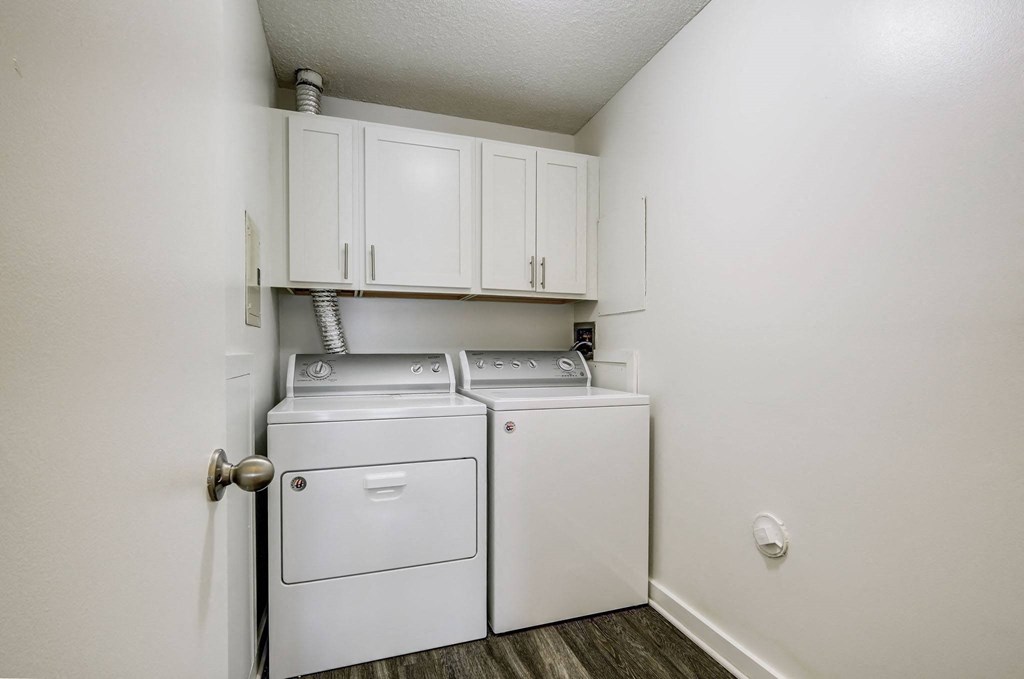 a white washer and dryer in a laundry room with white cabinets
