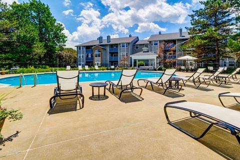 A pool area with chairs and a table in front of a building.
