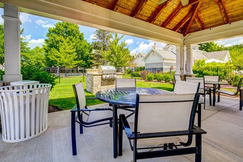 A patio with a table and chairs under a roof.