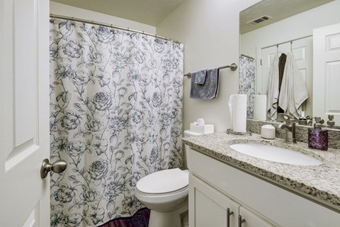 A bathroom with a floral shower curtain and a white toilet.