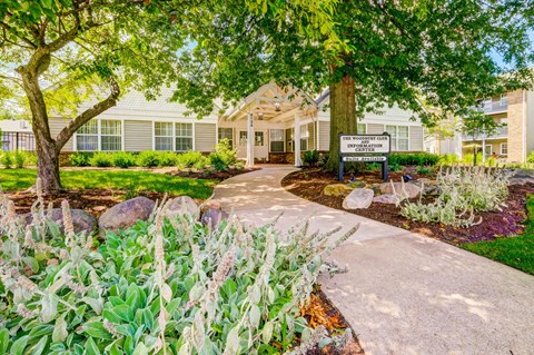 A garden with a sign in front of a building.