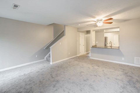 A spacious room with a staircase and a ceiling fan.