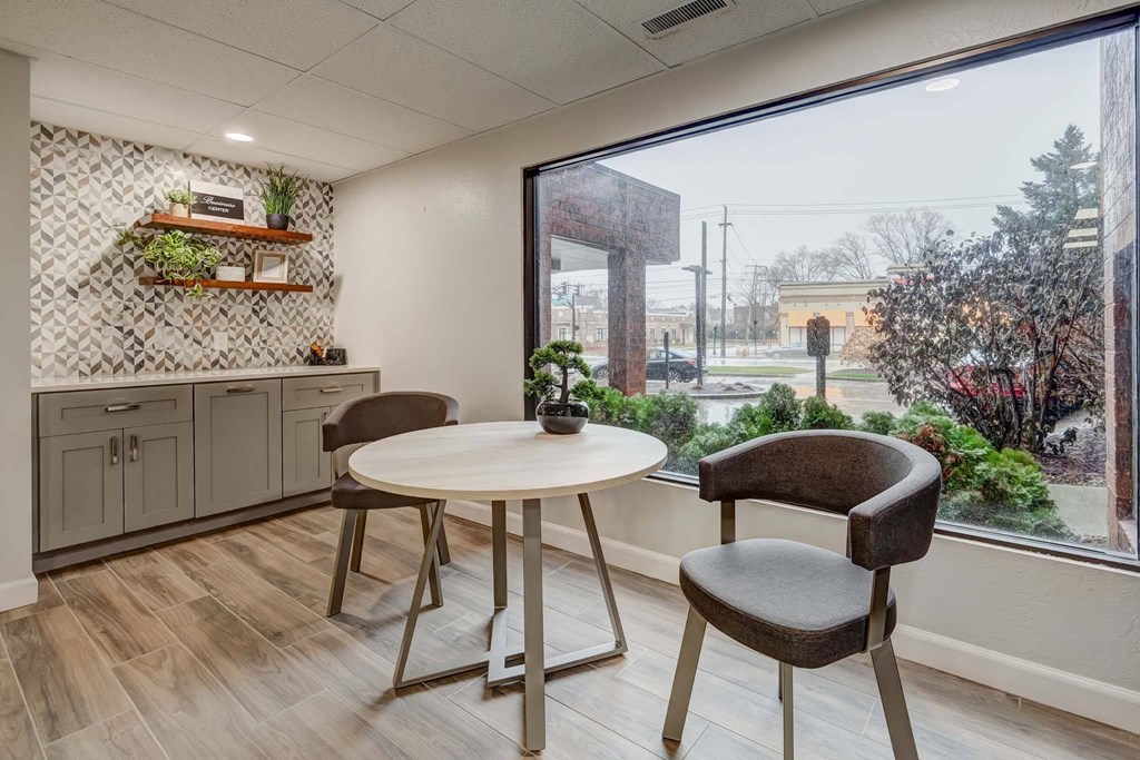 a dining area with a table and chairs next to a large window
