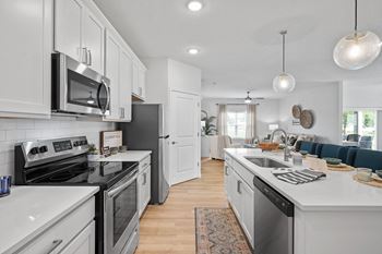 an open kitchen and living room with white cabinets and stainless steel appliances