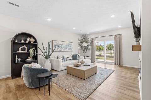 A living room with a grey chair, a black shelf, a white sofa, and a wooden coffee table.