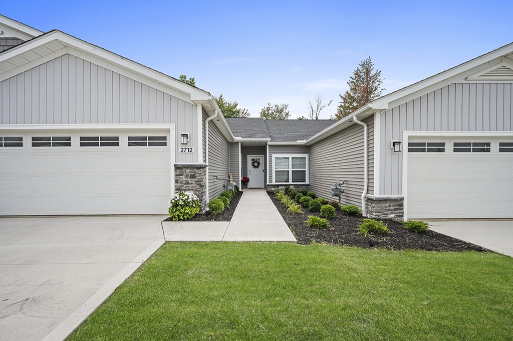 a white house with two garage doors and a lawn