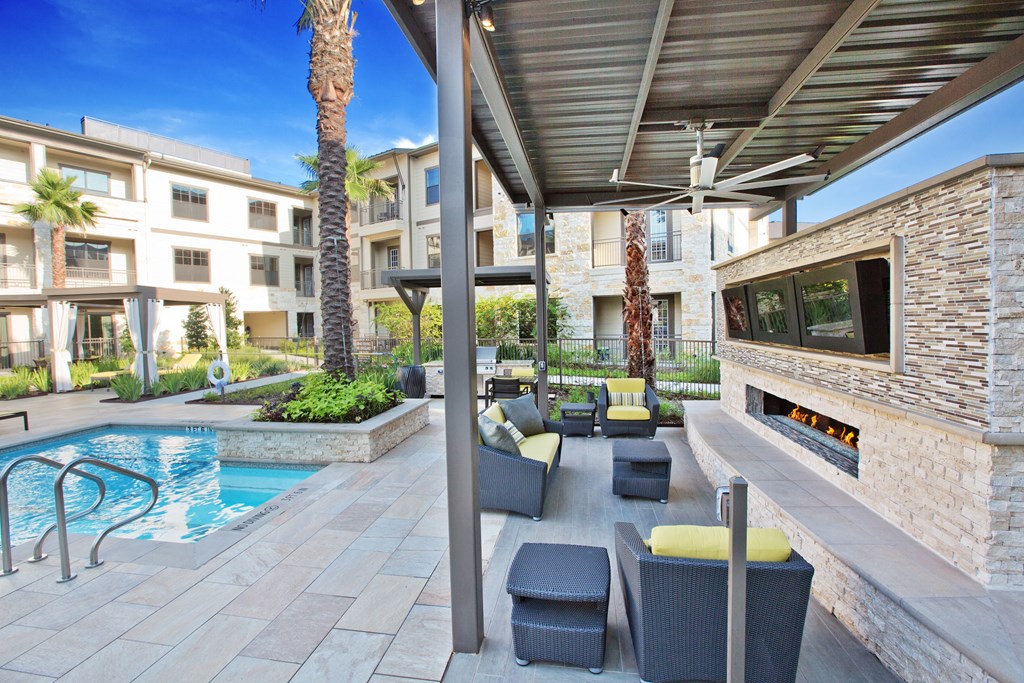 a patio with chairs and a fireplace next to a pool