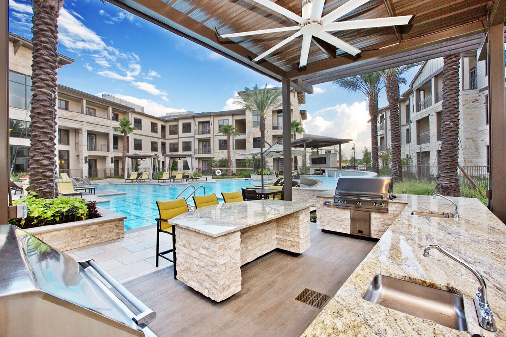 a patio with a bar and a pool with buildings in the background