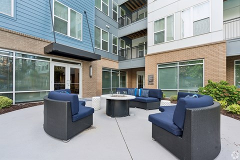 A patio with blue cushioned furniture and a table.