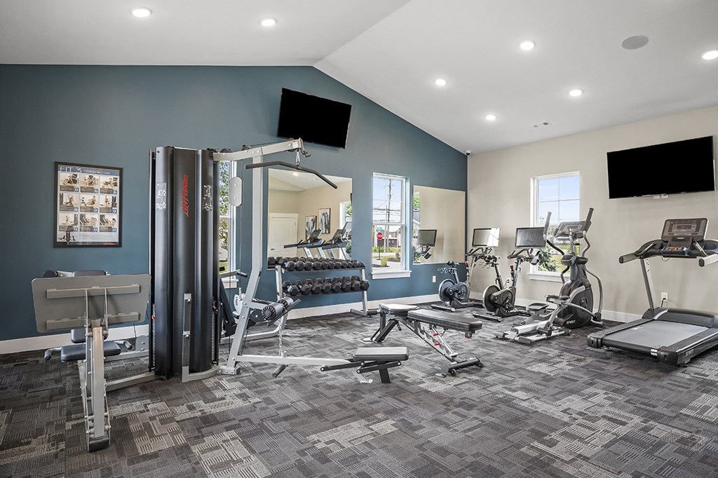 a gym with treadmills and other exercise equipment in a room with blue walls
